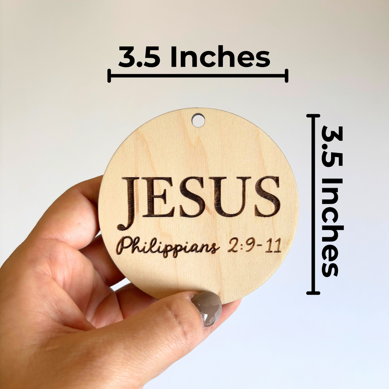 Wooden round ornament with 'JESUS' and Bible verse measurement on a plain background