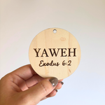 Round wooden sign with 'YAWEH Exodus 6:2' text held by a hand against a light background